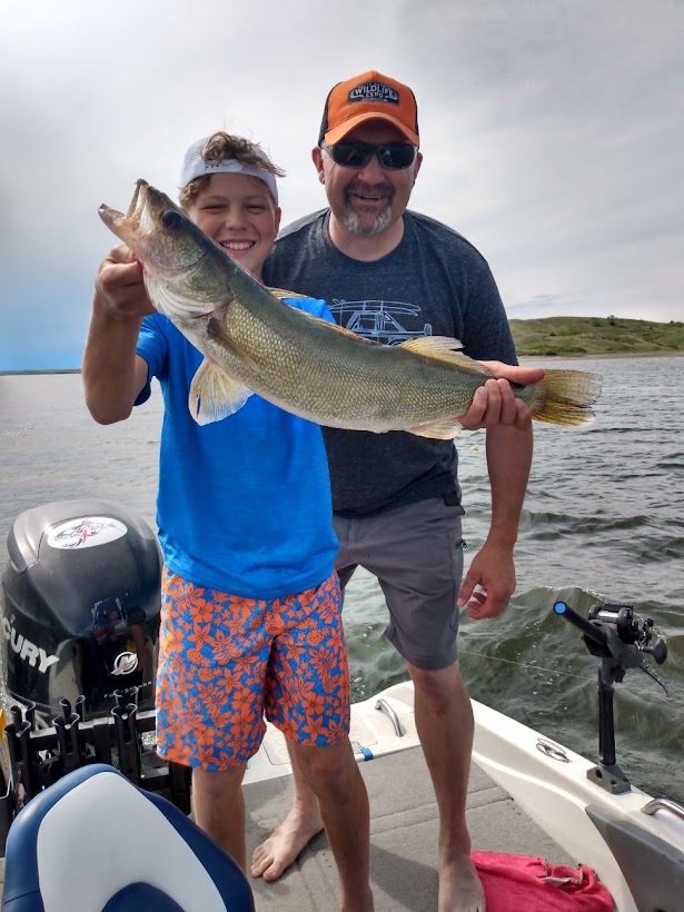 boy holding fish on boat